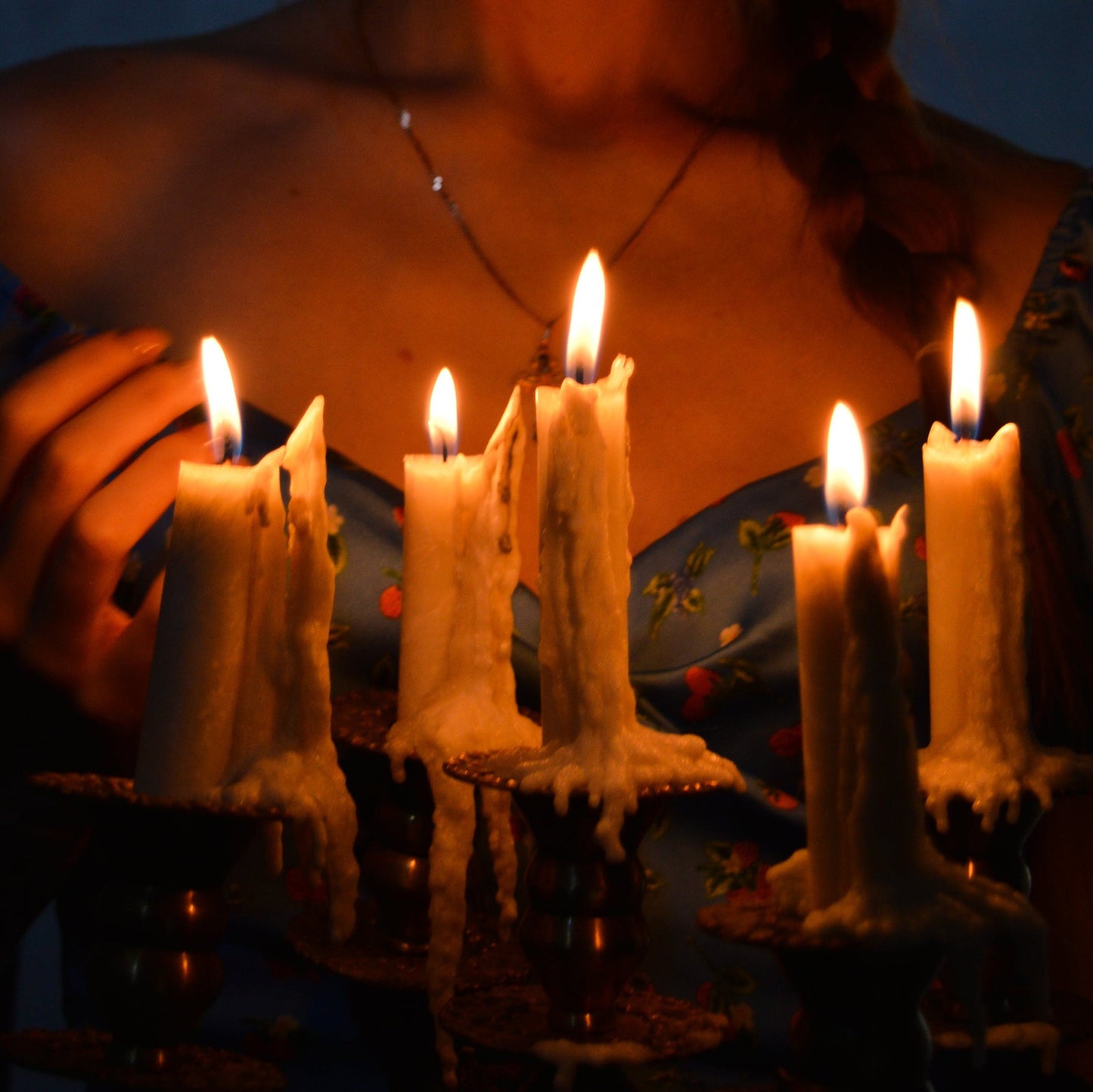 Person holding lit candles in a dark setting