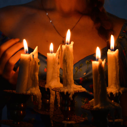 Person holding lit candles in a dark setting